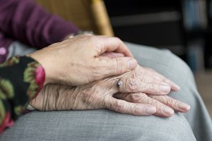 Zwei Hände unterschiedlicher Generationen berühren sich in einem Moment stiller Verbundenheit